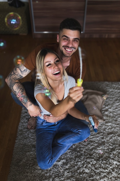 Glückliche junge Paare, die das Durchbrennen der Luftblasen auf Wolldecke genießen