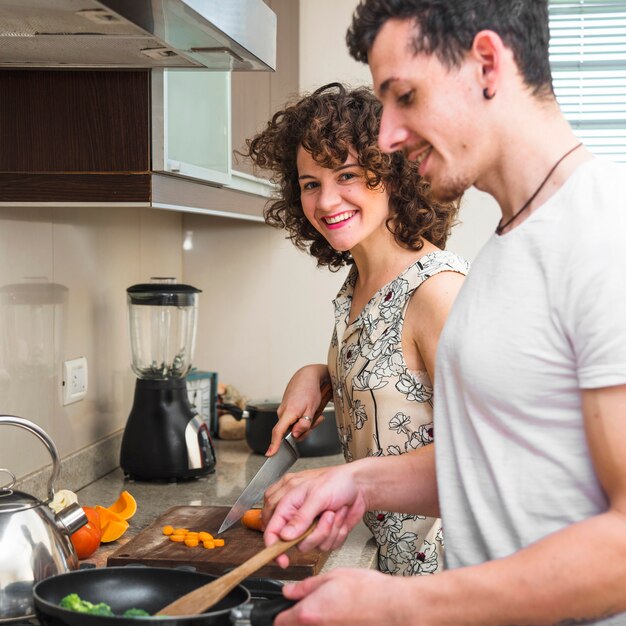 Glückliche junge Paare, die Lebensmittel in der Küche zubereiten