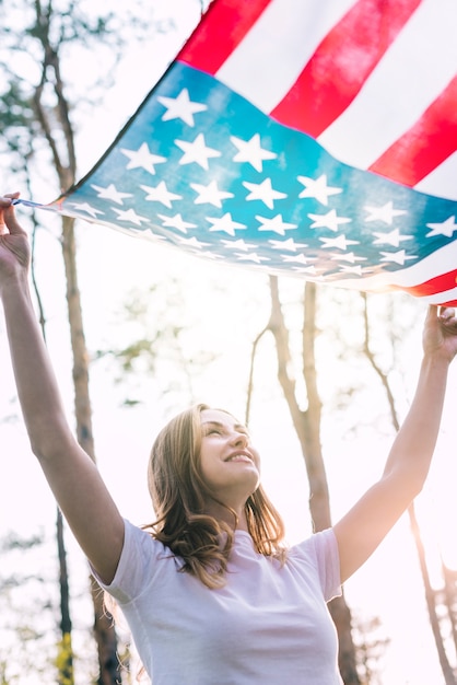 Glückliche junge weibliche wellenartig bewegende Flagge von USA