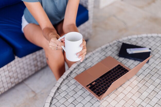 Glückliche kaukasische Frau macht Fernarbeit auf Laptop zu Hause bequemer Ort, der Tee trinkt