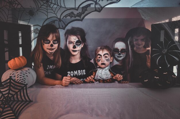 Glückliche Kinder in gruseligen Halloween-Kostümen und Make-up genießen ihre kleine Party.