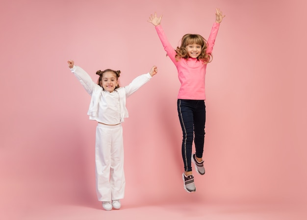 Kostenloses Foto glückliche kinder lokalisiert auf korallenrosa studiowand