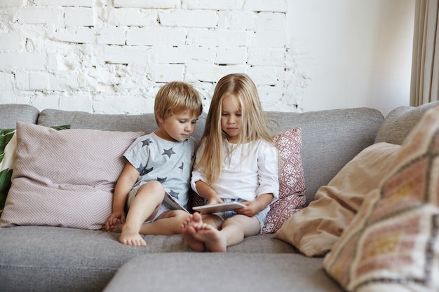 Glückliche kleine Kinder sitzen im Wohnzimmer