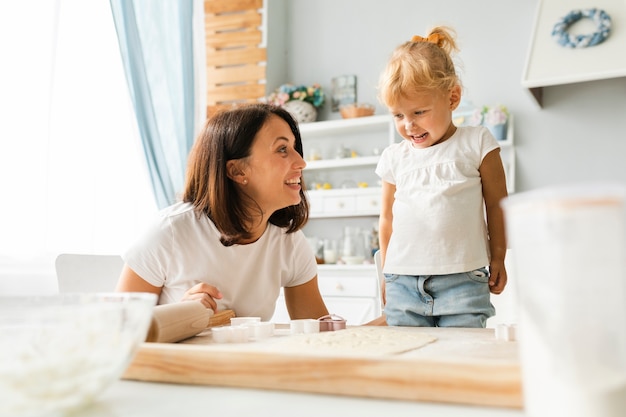 Glückliche kleine Tochter und Mutter, die zusammen kocht