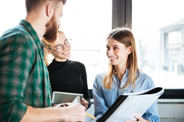 Glückliche Kollegen im Büro sprechen miteinander und halten Ordner