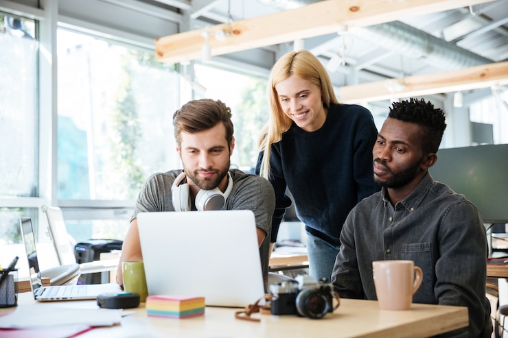 Kostenlose Foto glückliche kollegen sitzen im büro und arbeiten zusammen