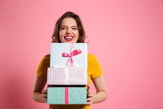 Glückliche lachende frau mit roten lippen, die bündel von geschenkboxen halten,