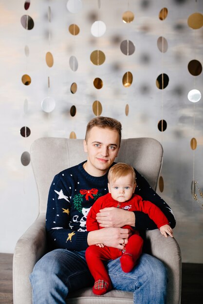 Glückliche lächelnde Familie am Studio auf Hintergrund des Weihnachtsbaums mit Geschenk