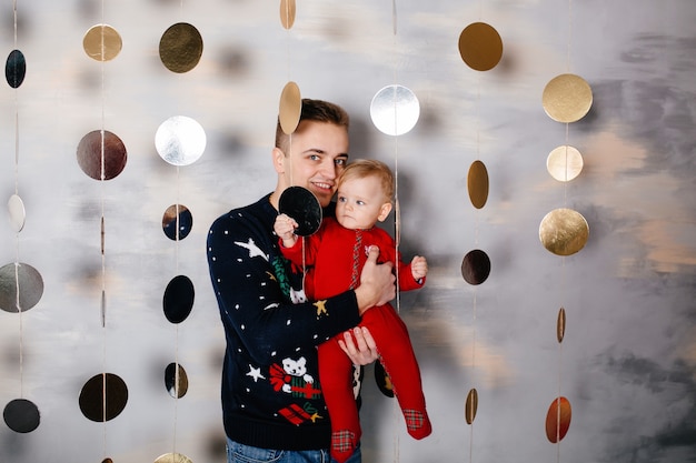 Glückliche lächelnde Familie am Studio auf Hintergrund des Weihnachtsbaums mit Geschenk