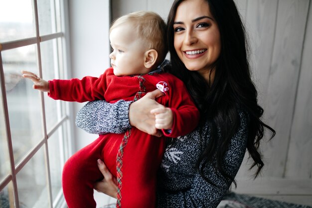 Glückliche lächelnde Familie am Studio auf Hintergrund des Weihnachtsbaums mit Geschenk