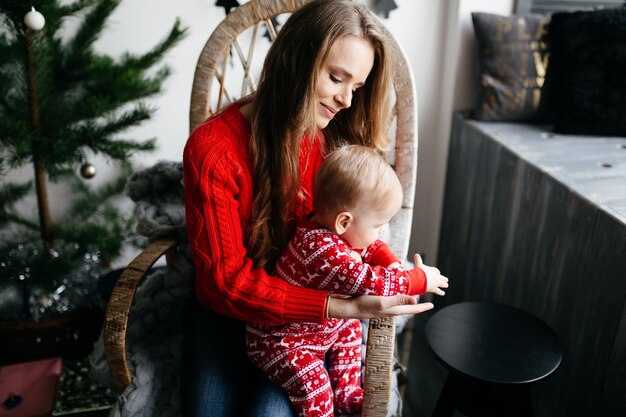 Glückliche lächelnde Familie am Studio auf Hintergrund des Weihnachtsbaums mit Geschenk