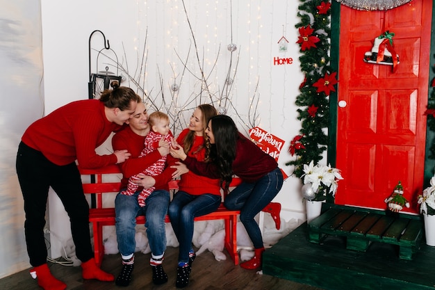 Glückliche lächelnde Familie am Studio auf Hintergrund des Weihnachtsbaums mit Geschenk