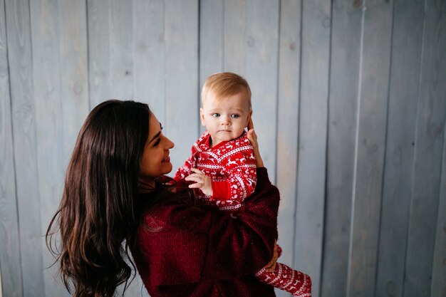 Glückliche lächelnde Familie am Studio auf Hintergrund des Weihnachtsbaums mit Geschenk