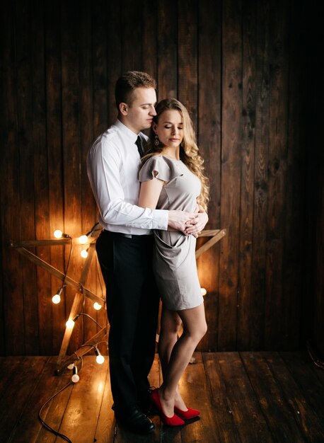 Glückliche lächelnde Familie am Studio auf Hintergrund des Weihnachtsbaums mit Geschenk