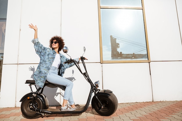 Glückliche lächelnde Frau, die auf einem modernen Motorrad sitzt