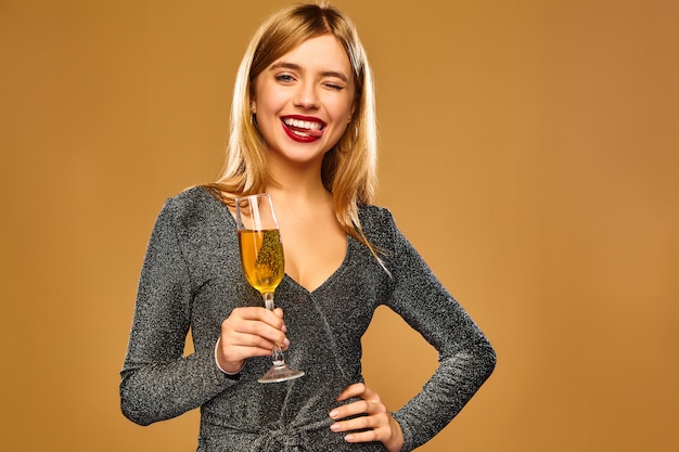 Glückliche lächelnde Frau im stilvollen glamourösen Kleid mit Champagnerglas.