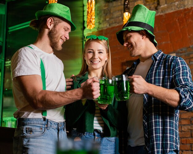 Glückliche Leute feiern st. Patrick's Day mit Getränken