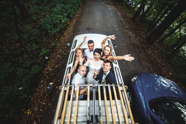 Glückliche Leute im Auto feiern Hochzeit