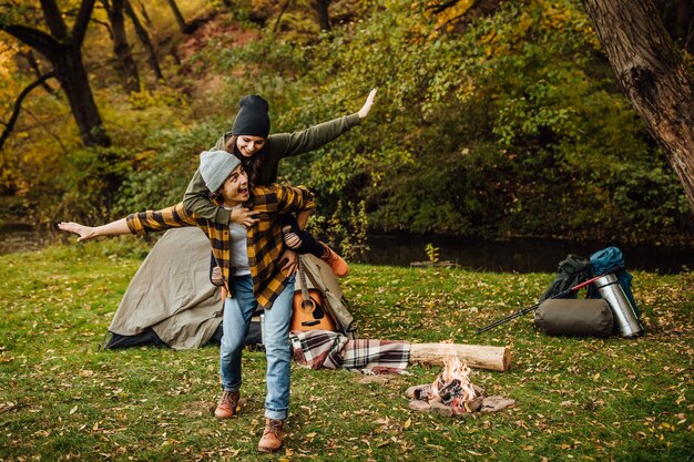Glückliche Liebespaare von Touristen haben Spaß im Wald in der Nähe des Zeltes und machen Flugzeuge