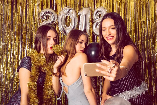 Glückliche Mädchen, die selfie auf Neujahrsparty nehmen