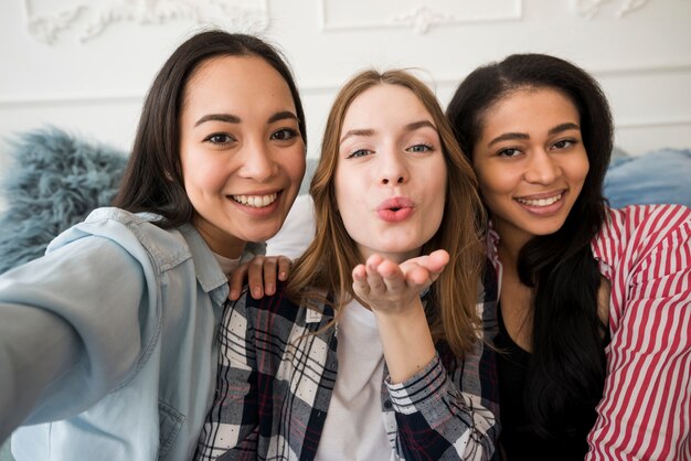 Glückliche Mädchen, die selfie nehmen und einen Kuss durchbrennen, der Kamera betrachtet