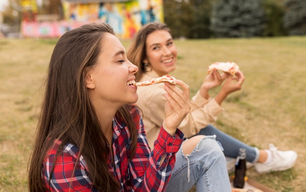 Glückliche Mädchen essen Pizza im Freien