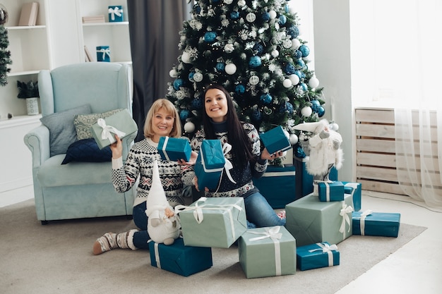 Glückliche Mama und Tochter packen Weihnachtsgeschenke aus