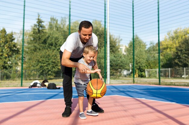 Glückliche monoparentale Familie, die lernt, wie man Basketball spielt