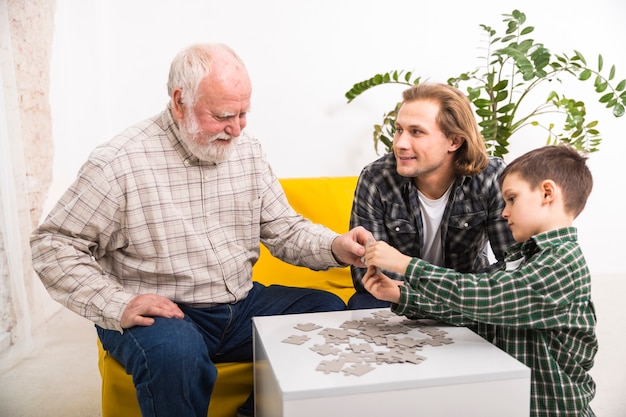 Glückliche multi-generationsfamilie, die zusammen Puzzle zusammenbaut