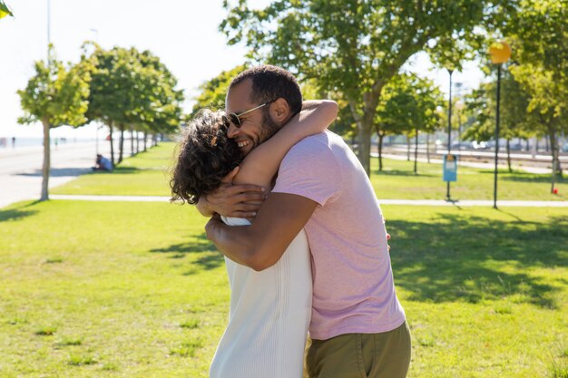 Glückliche multiethnische Freunde, die im Park umarmen