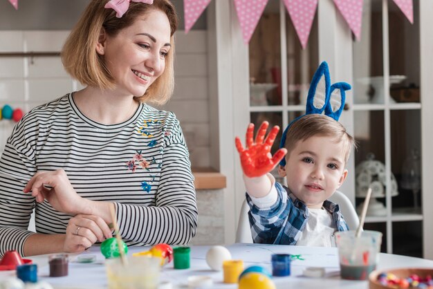 Glückliche Mutter, die Ostereier mit Sohn malt