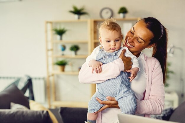 Glückliche Mutter genießt, während sie ihren kleinen Sohn hält und Zeit mit ihm zu Hause verbringt