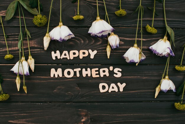 Glückliche Mutter-Tagesaufschrift mit Blumen auf Tabelle