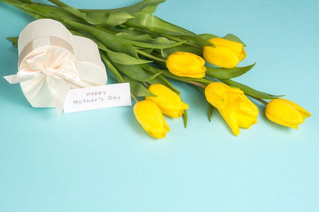 Glückliche Mutter-Tagesaufschrift mit gelben Tulpen und Geschenk