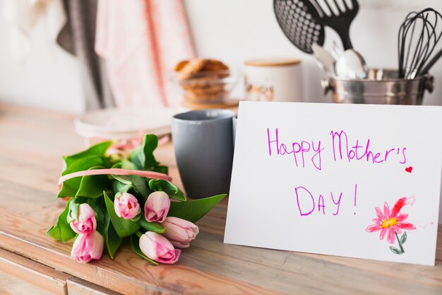 Glückliche Mutter-Tagesaufschrift mit Tulpen auf Tabelle