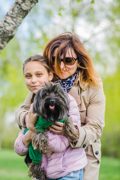 Glückliche Mutter umarmt ihre Tochter und Hund