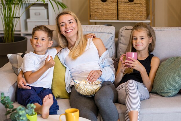 Glückliche Mutter und ihre Kinder, die Popcorn essen