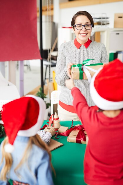 Glückliche Mutter und Kinder, die Weihnachtsgeschenke austauschen