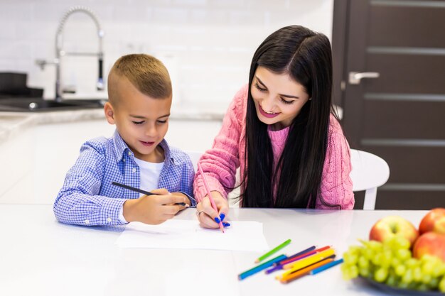 Glückliche Mutter und Sohn, die mit Farbstiften zeichnen, haben Spaß zu Hause