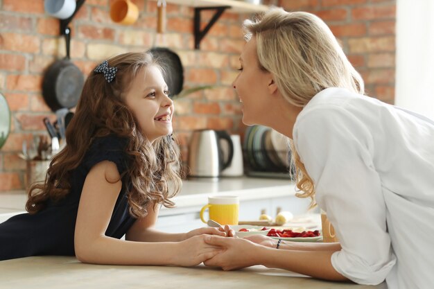 Glückliche Mutter und Tochter, die Hände in der Küche halten