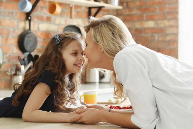 Glückliche Mutter und Tochter, die Hände in der Küche halten