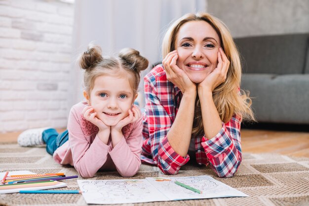 Glückliche Mutter und Tochter, die Kamera im Wohnzimmer betrachtet