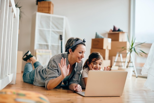 Glückliche Mutter und Tochter winken während des Videoanrufs in ihrem neuen Zuhause