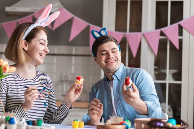 Glückliche Mutter und Vater malen Eier für Ostern