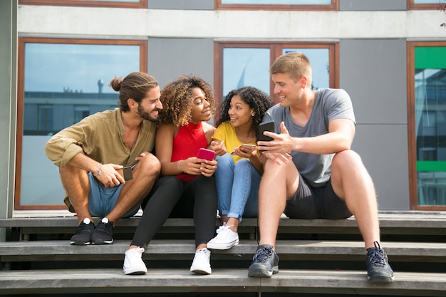 Glückliche nette Freunde, die Nachrichten auf Telefonbildschirmen lesen