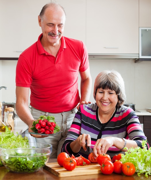 glückliche reife Paare, die in der Küche kochen