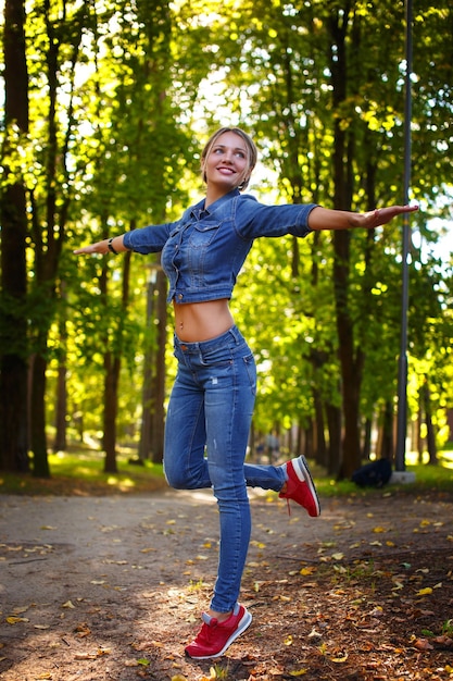 Kostenloses Foto glückliche schlanke frau in denim-kleidung, die im grünen naturpark posiert.