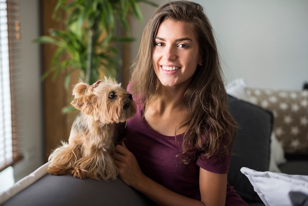 Glückliche schöne junge Frau, die mit ihrem kleinen Hund aufwirft