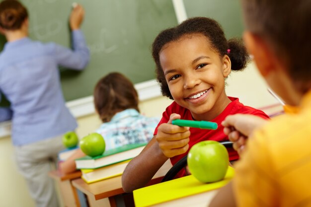 Glückliche Schüler ihre grünen Bleistift teilen