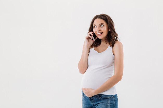 Glückliche schwangere Frau, die per Handy spricht